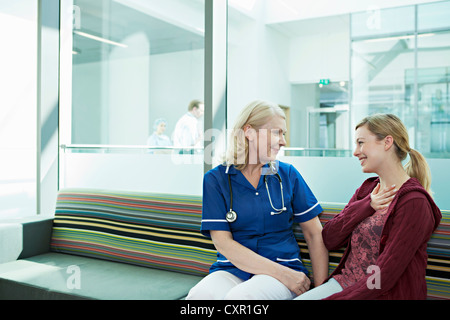 Nurse talking to woman in hospital waiting room Stock Photo