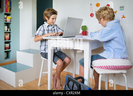 Brothers doing their homework in kitchen Stock Photo