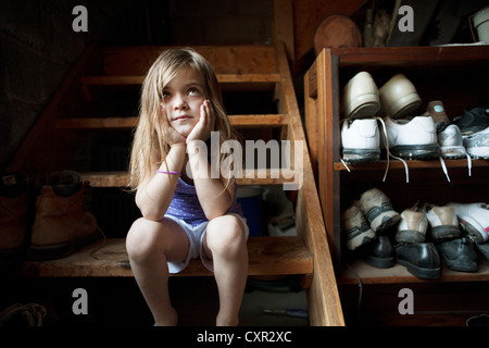 Little girl sitting on basement steps, looking up