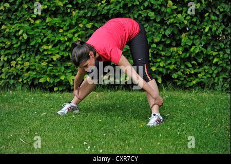 Young woman warming up, stretching before running, Stuttgart, Baden-Wuerttemberg, Germany, Europe, PublicGround Stock Photo