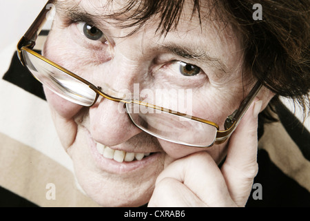 Smiling elderly woman looking over the rim of her glasses Stock Photo