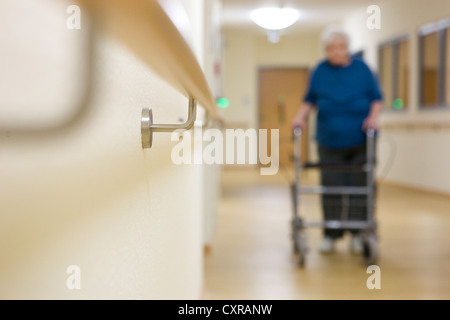 Elderly woman walking with a wheeled walker at a nursing home Stock Photo