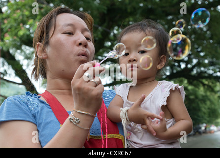 A mother blows bubbles for her daughter in Luang Prabang, Laos Stock Photo