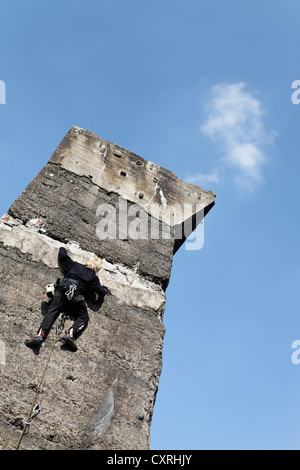 Boy climbing a high concrete pillar, climbing wall at a former ore bunker, former steel works, Landscape Park Duisburg-Nord Stock Photo