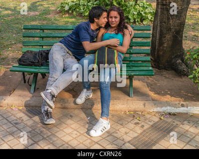 Two teenage lovers embrace on a park bench in a city park in Asunción, Paraguay. Stock Photo