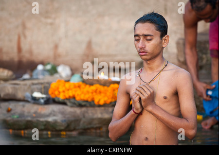 Young Hindu man with closed eyes during a morning prayer, the Ganges, Varanasi, Benares or Kashi, Uttar Pradesh, India, Asia Stock Photo