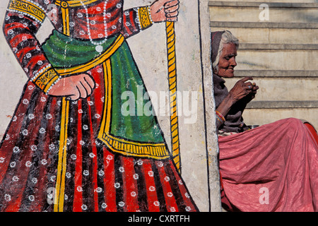 Wall painting beside an elderly woman, beggar woman, Udaipur, Rajasthan, India, Asia Stock Photo