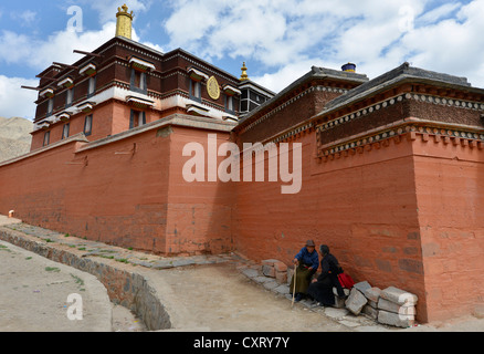 Tibetan Buddhism, pilgrims, group, two elderly women in traditional Chuba dress sitting at the monastery walls Stock Photo