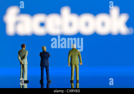 Businessmen, miniature figures standing in front of a blurred Facebook logo, symbolic image Stock Photo