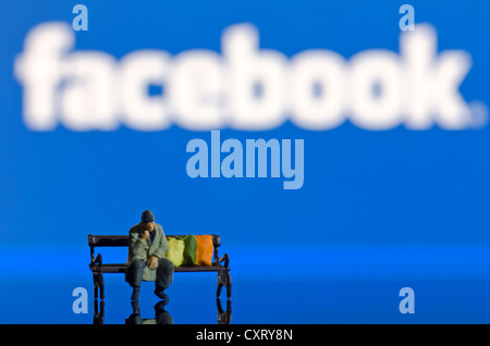 Homeless man sitting on a bench, miniature figure in front of a blurred Facebook logo, symbolic image