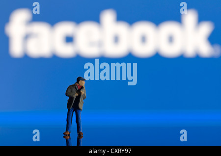 Thief, miniature figure standing in front of a blurred Facebook logo, symbolic image Stock Photo