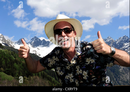 Smiling man wearing a straw hat, sunglasses, thumbs up, in the Tyrolean mountains, Kaunertal, Tyrol, Austria, Europe Stock Photo
