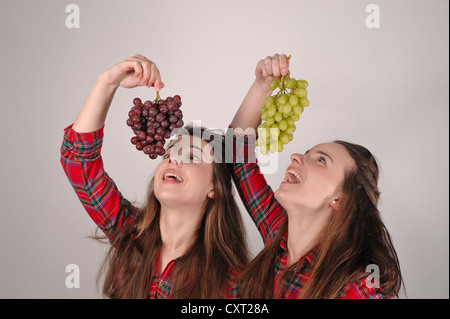Twin sisters holding grapes Stock Photo