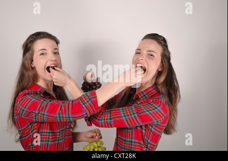 Twin sisters holding grapes Stock Photo