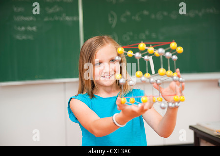 Schoolgirl in a classroom with a model of an atom Stock Photo
