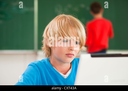 Schoolboy using a laptop in a classroom Stock Photo