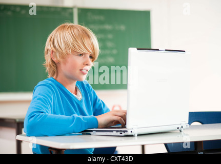 Schoolboy using a laptop in a classroom Stock Photo