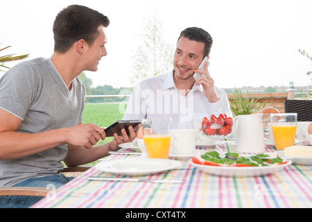 Two young men having breakfast on a terrace Stock Photo