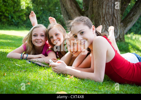Girls lying on a meadow and chatting with a tablet PC Stock Photo