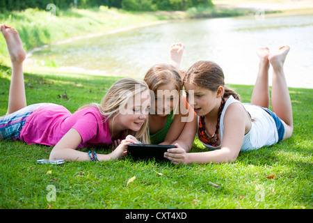 Girls lying on a meadow and chatting with a tablet PC Stock Photo