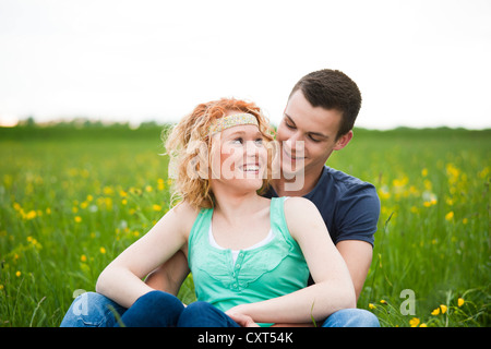 Smiling young couple sitting on a meadow Stock Photo