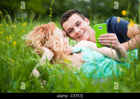 Young couple lying on a meadow and checking an SMS on a mobile phone Stock Photo