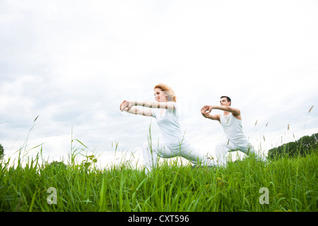 Young couple doing yoga in a meadow Stock Photo