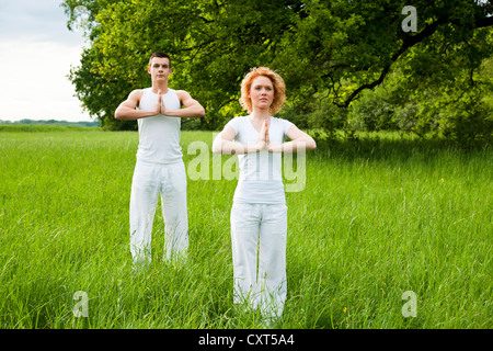 Young couple doing yoga in a meadow Stock Photo