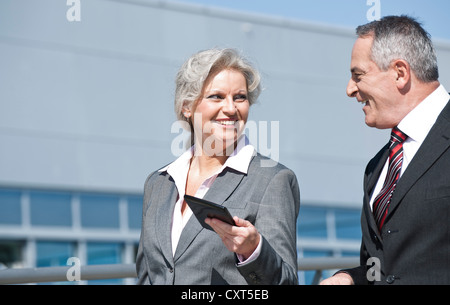 Businesswoman holding a tablet PC while having a conversation with a businessman Stock Photo