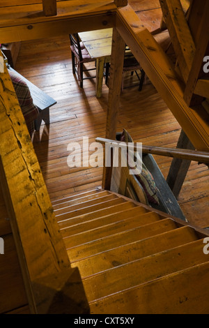 Pinewood stairs leading to the living room on the ground floor of an old Canadiana cottage-style residential log home, circa Stock Photo
