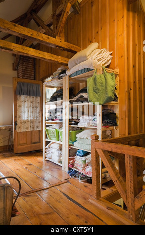 Clothing stored on an opened shelf in the upstairs bedroom of an old Canadiana cottage-style residential log home, circa 1825, Stock Photo