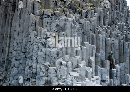 Woman standing on basalt columns, Hálsanefshellir cave, Reynisfjara beach at Vik í Mýrdal, South Coast, Iceland, Europe Stock Photo