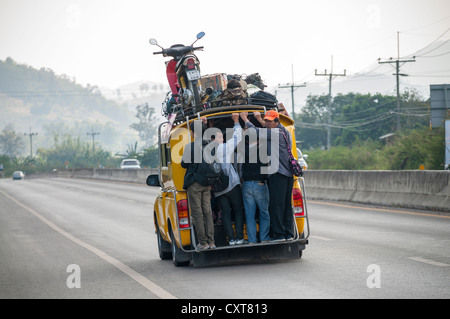 Overcrowded share taxi or Songthaew on a road, a motor bike loaded on the roof, northern Thailand, Thailand, Asia Stock Photo