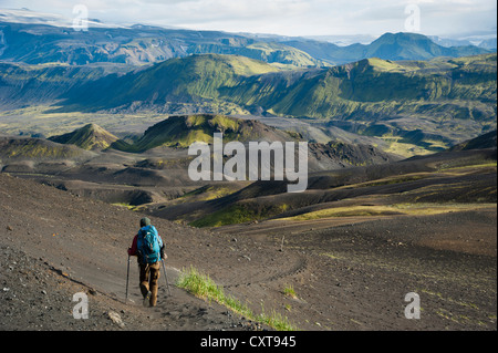 View towards Mýrdalsjoekull Glacier, hiker in the Black Lava Desert, with moss-covered mountains along the Laugavegur hiking Stock Photo