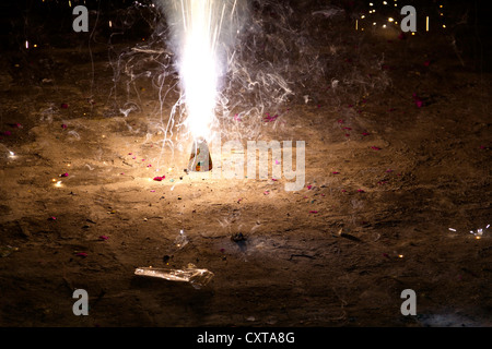 Lighted firecracker and discarded packaging at the festival of Diwali. The sparks and flame from the firecracker is intense. Stock Photo