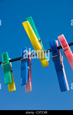 Close up of plastic clothes pegs peg on washing line with blue sky background England UK United Kingdom GB Great Britain Stock Photo
