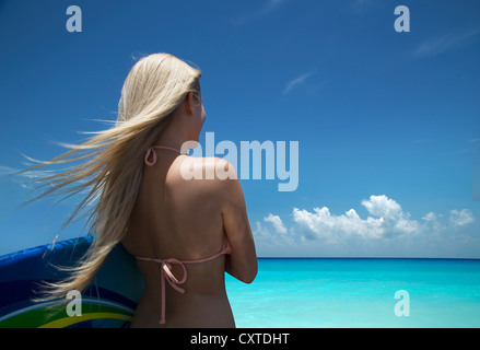 Woman carrying boogie board on beach Stock Photo