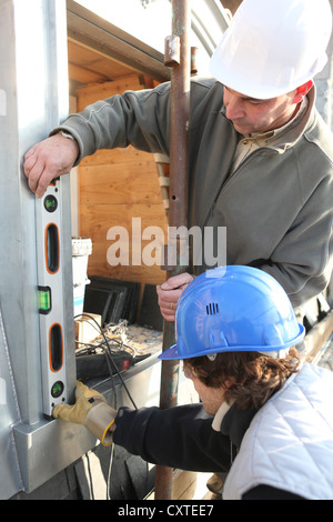 Builders using spirit level Stock Photo - Alamy