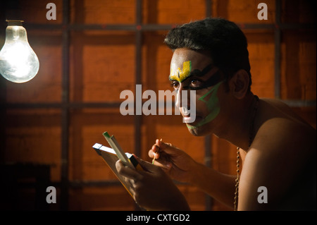 Horizontal close up portrait of a Kathakali performance artist applying make up before the performance. Stock Photo