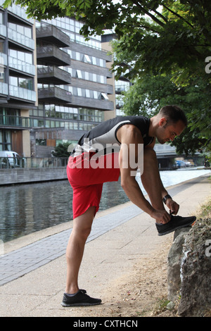 Runner tying his shoes on city street Stock Photo