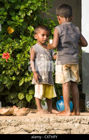 Vertical portrait of two small Indian boys brushing their teeth on the riverbank in Kerala. Stock Photo