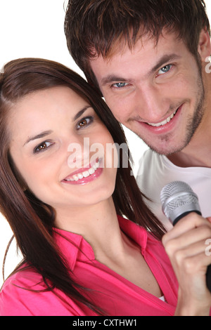 Couple singing into a microphone Stock Photo