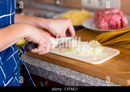 Young woman is cooking and chopping onions for lunch or dinner, cropped image Stock Photo