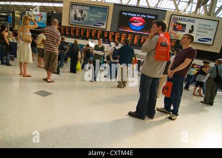 Horizontal wide angle of people waiting for train information on the destinations board at Waterloo Mainline Station. Stock Photo