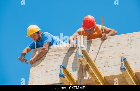 Construction workers nailing cement formwork in place Stock Photo