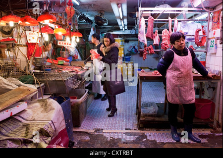 Butchers in Hong Kong's Central Market prepare cuts of meat during a slow period at their butcher shop. Stock Photo