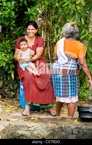 Vertical portrait of three generations of an Indian family doing their daily chores by the riverside in Kerala. Stock Photo