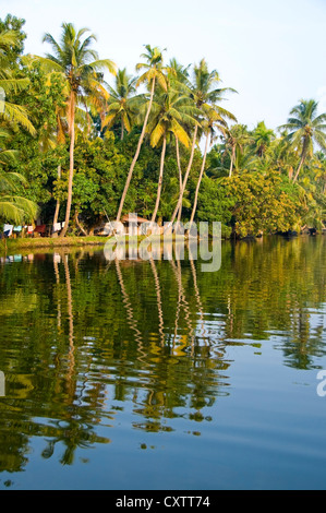 Horizontal wide angle of small traditional homes along the riverbank in the backwaters of Kerala Stock Photo