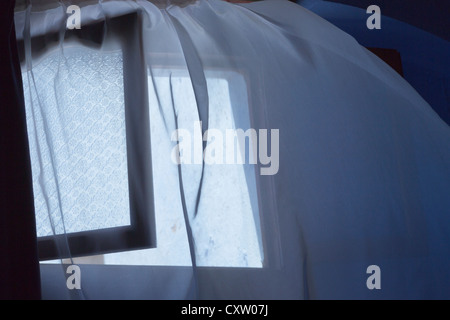 Curtain by open window billowing out in a breeze. Stock Photo