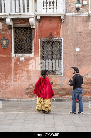 A young man and woman dressed in costume walking the streets of Venice to advertise the Opera. Stock Photo